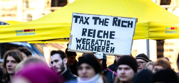 «Tax the Rich (Besteuerung der Reichen) - Reiche wegrationalisieren» steht auf einem Protestplakat bei einer Wahlkampfveranstaltung der FDP am 13.1.2025 auf dem Bremer Marktplatz. 