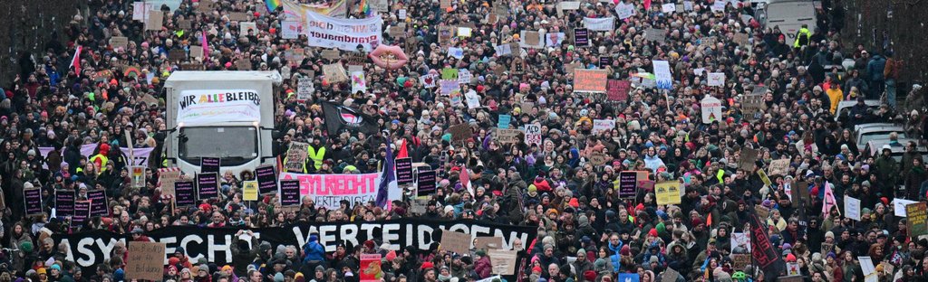 Teilnehmer gehen während einer Demonstration am 2.2.2025 in Berlin unter dem Motto «Aufstand der Anständigen - Demo für die Brandmauer» auf der Straße des 17. Juni - zwischen ihnen ein Transparent mit dem Aufdruck «Asylrecht verteidigen». Der Bundestag hatte einige Tage zuvor mit Unterstützung der AfD einem Antrag der Union zugestimmt, der Zurückweisungen von Asylsuchenden.